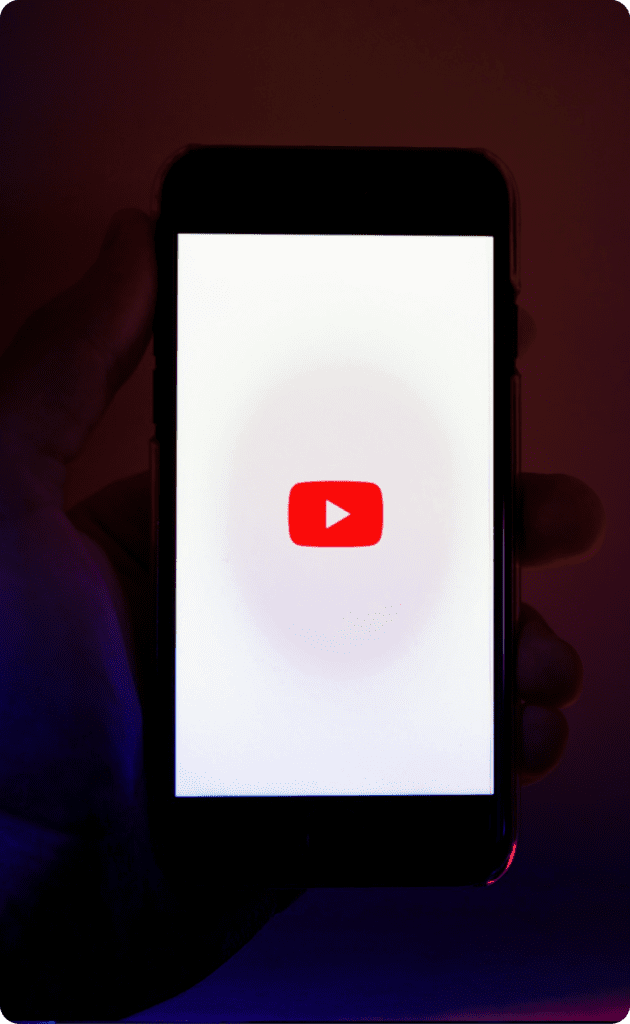 A hand holding a phone with the youtube logo inside